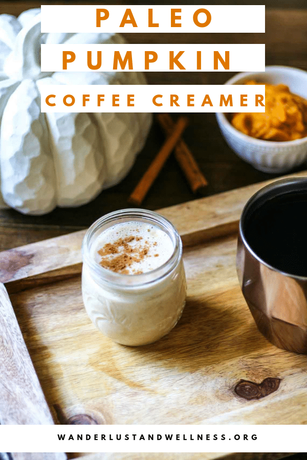 a small jar of paleo pumpkin coffee creamer sitting on a wooden cutting board. There is a cup of coffee next to it. 
