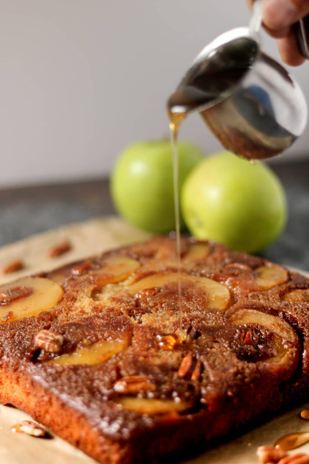 a person drizzling honey over an apple upside down cake