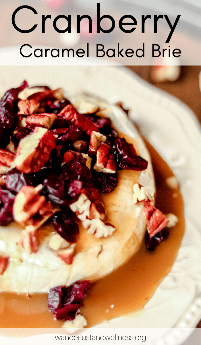 a baked brie round covered in caramel, cranberries, and pecans