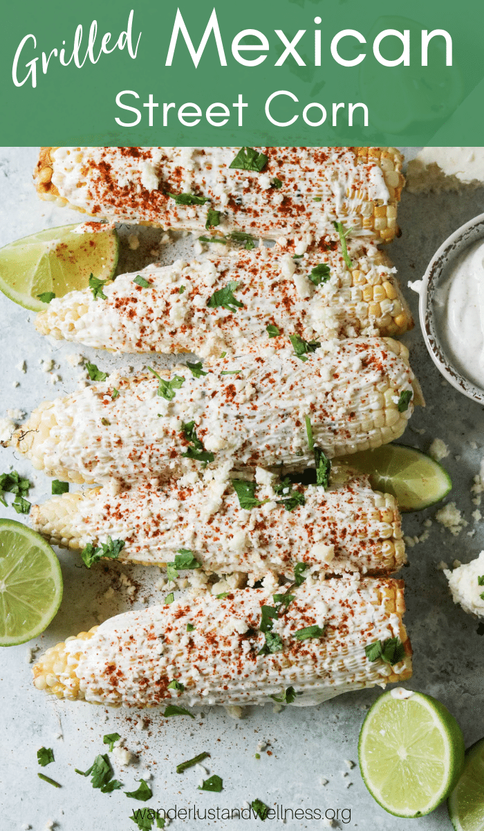 5 ears of grilled Mexican street corn on a table surrounded by sliced limes