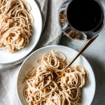 two bowls of cacio e pepe with a glass of red wine
