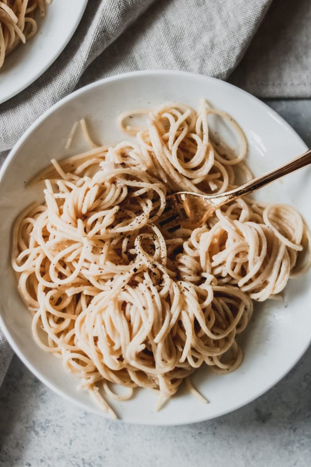 one bowl of cacio e pepe with a fork twirled in the noodles