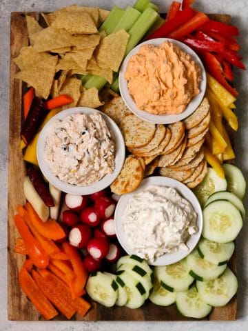 a party platter with fresh vegetables and chips and three varieties of the NEW PHILADELPHIA dips