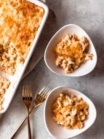 a dish of baked elbow macaroni and cheese and two individual servings in bowls