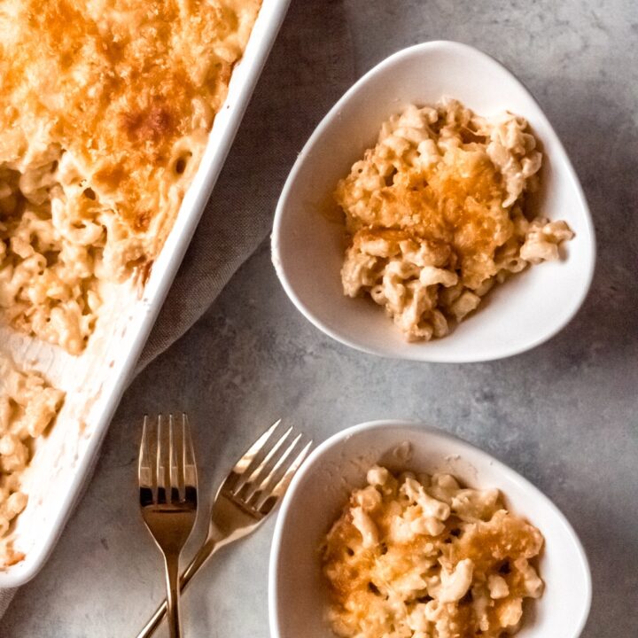 a dish of baked elbow macaroni and cheese and two individual servings in bowls