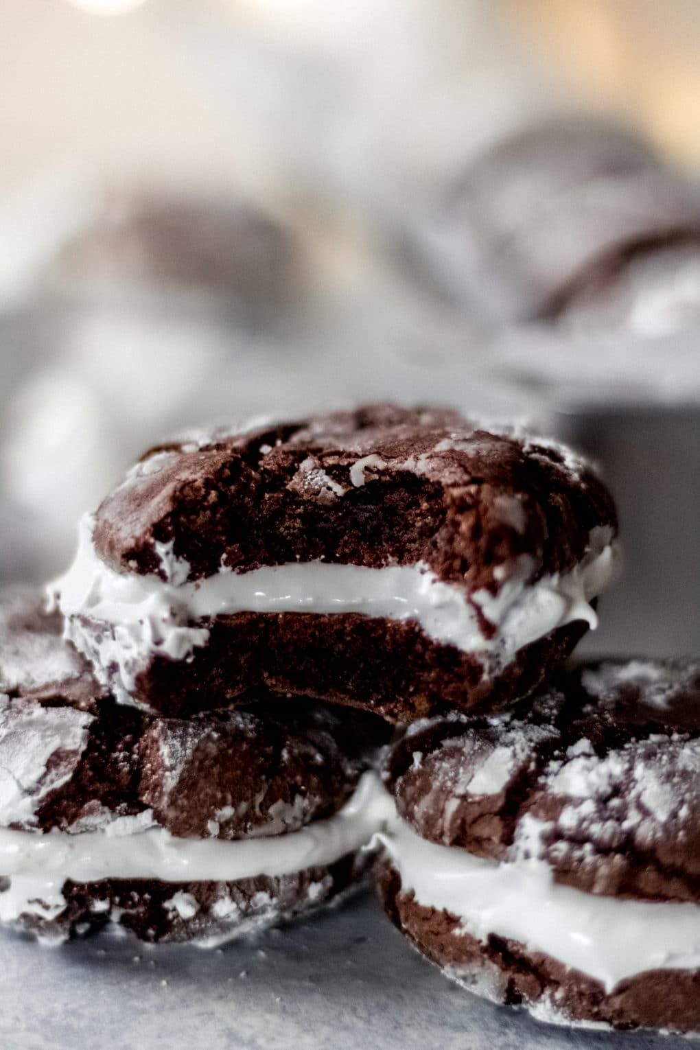 three hot cocoa sandwich cookies stacked with the top cookie having a bite taken out of it