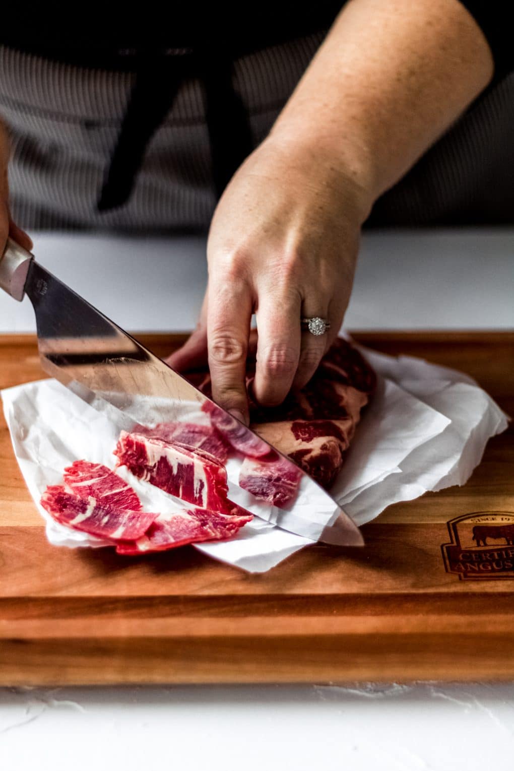 a woman slicing a certified angus beef ribeye steak
