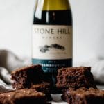 A two-layer stack of brownies with a bottle of red wine in the background