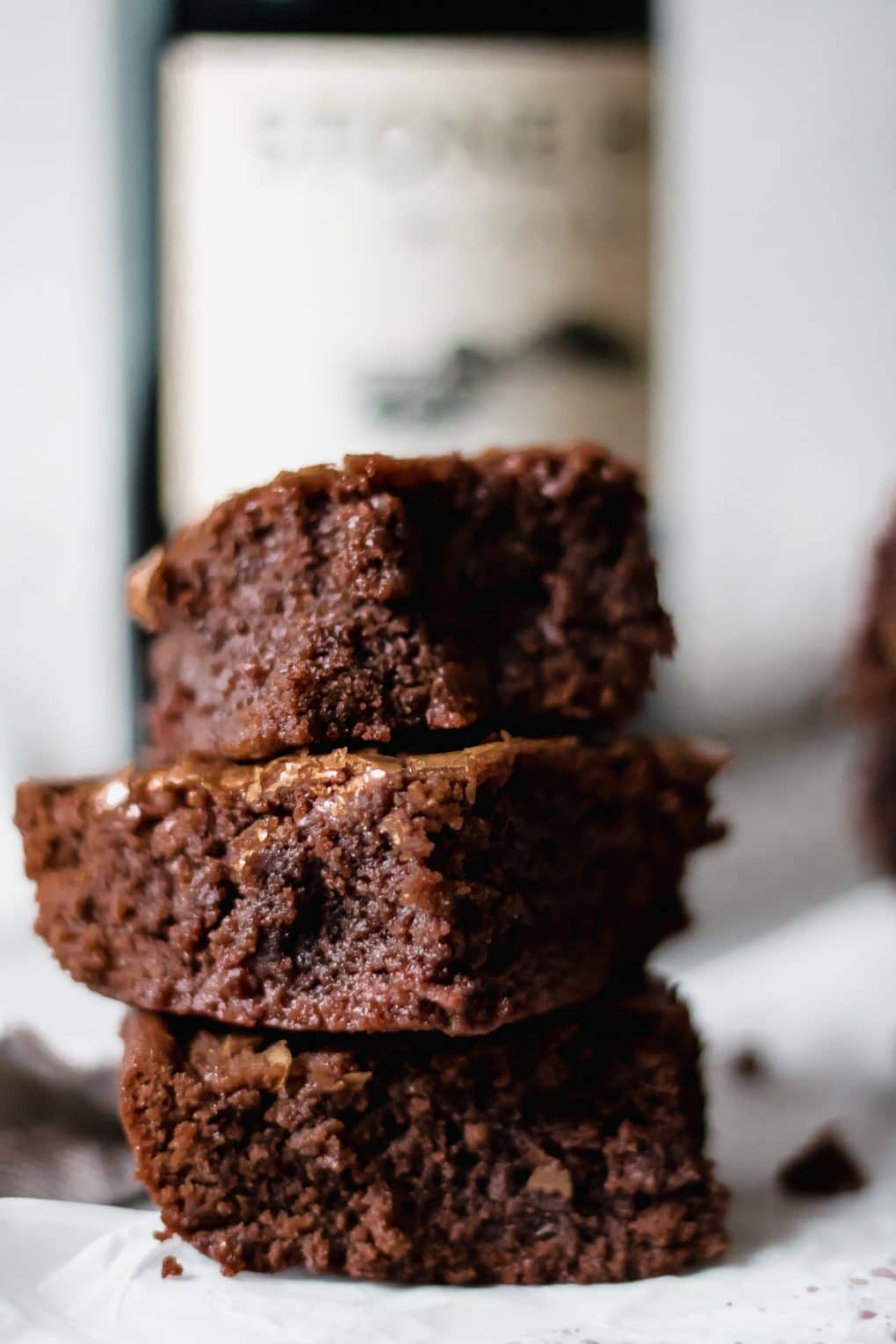 a stack of 3 red wine brownies with a bottle of red wine in the background