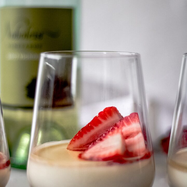 a glass of vanilla panna cotta with strawberry white wine sauce