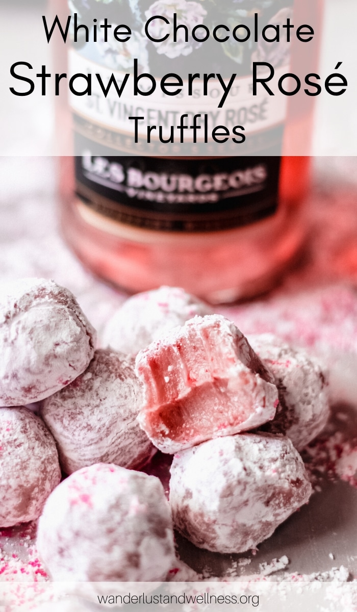 several white chocolate strawberry rosé truffles laying in front of a bottle of rosé