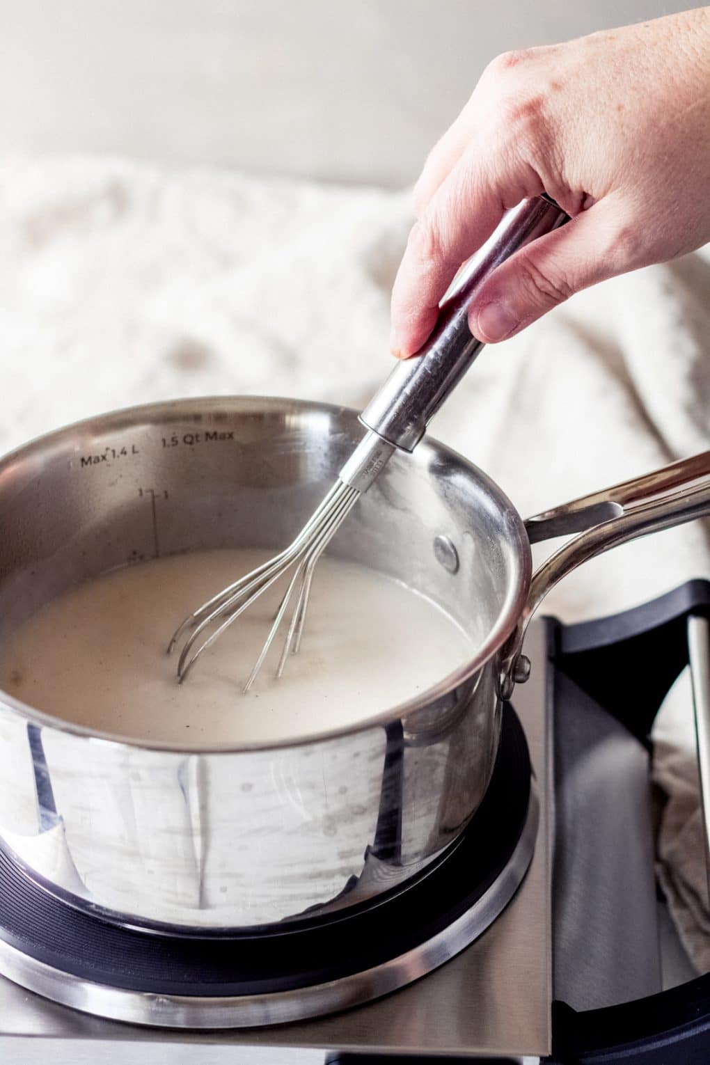 a woman whisking the dairy free vanilla coffee creamer