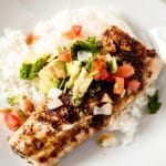 a grilled Mahi Mahi fillet on a bed of white rice in a white bowl topped with pico de gallo and chopped avocado