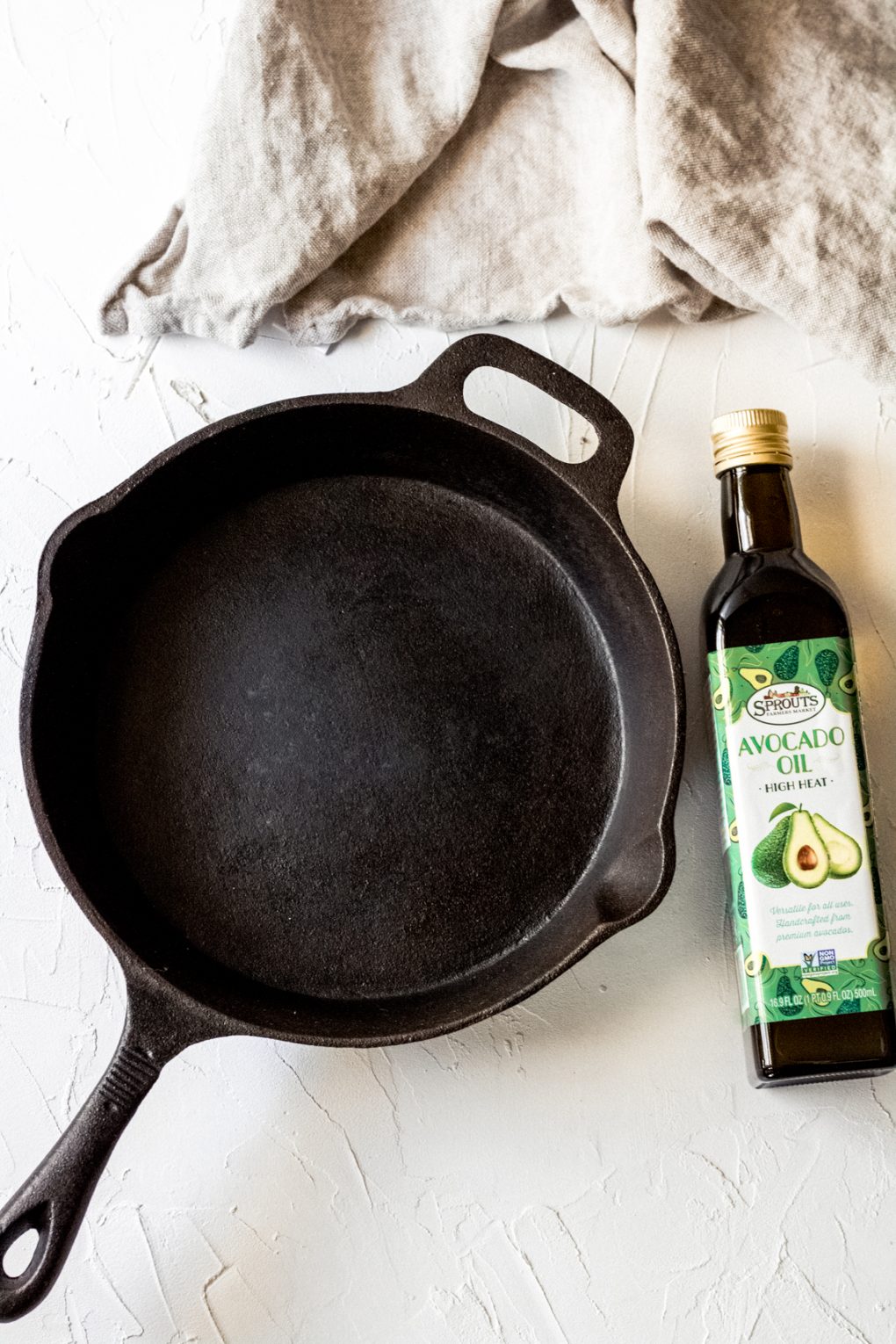 a cast iron skillet and bottle of avocado oil