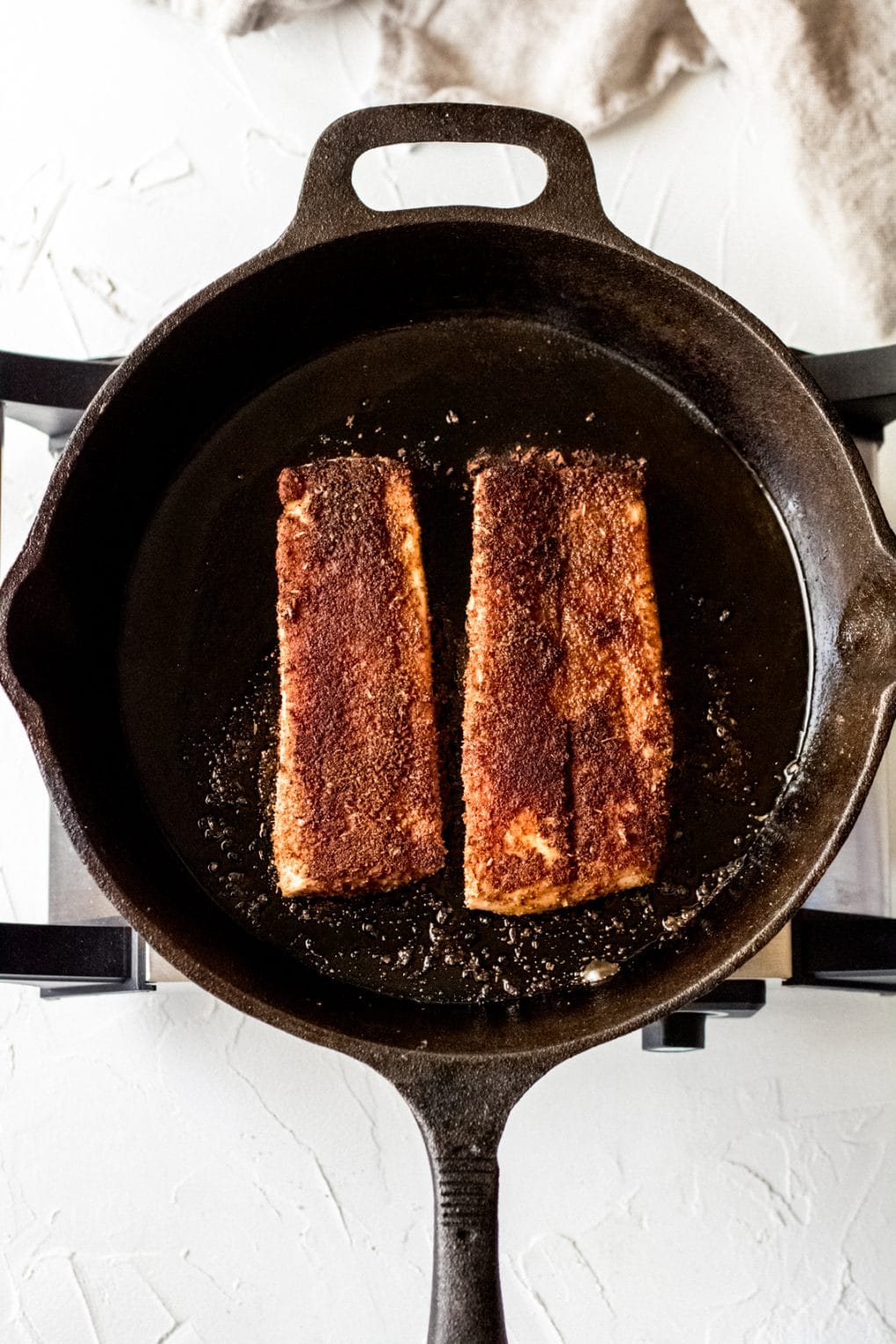 two Mahi mahi fillets cooking in a cast iron skillet
