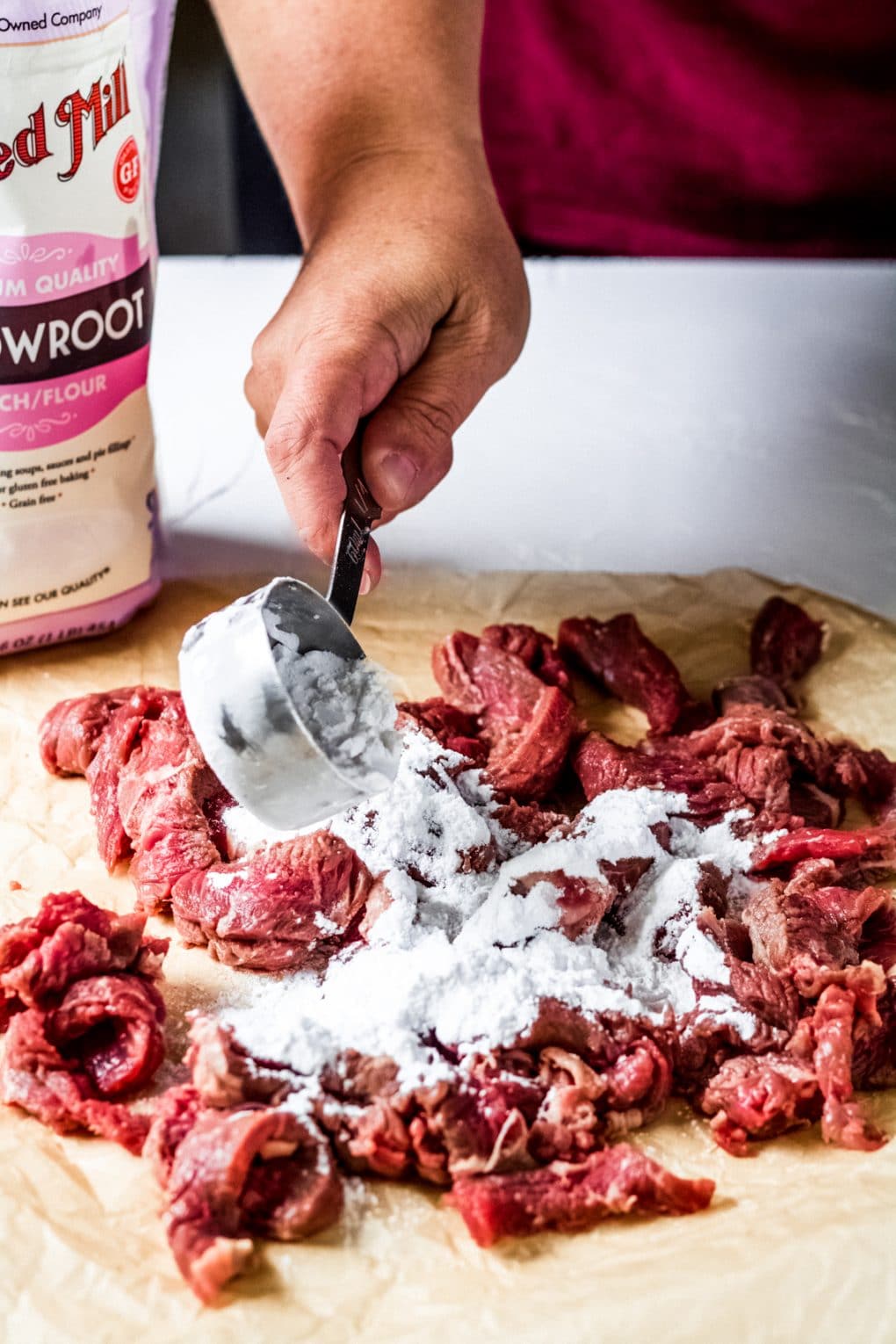 a woman coating steak with arrowroot starch
