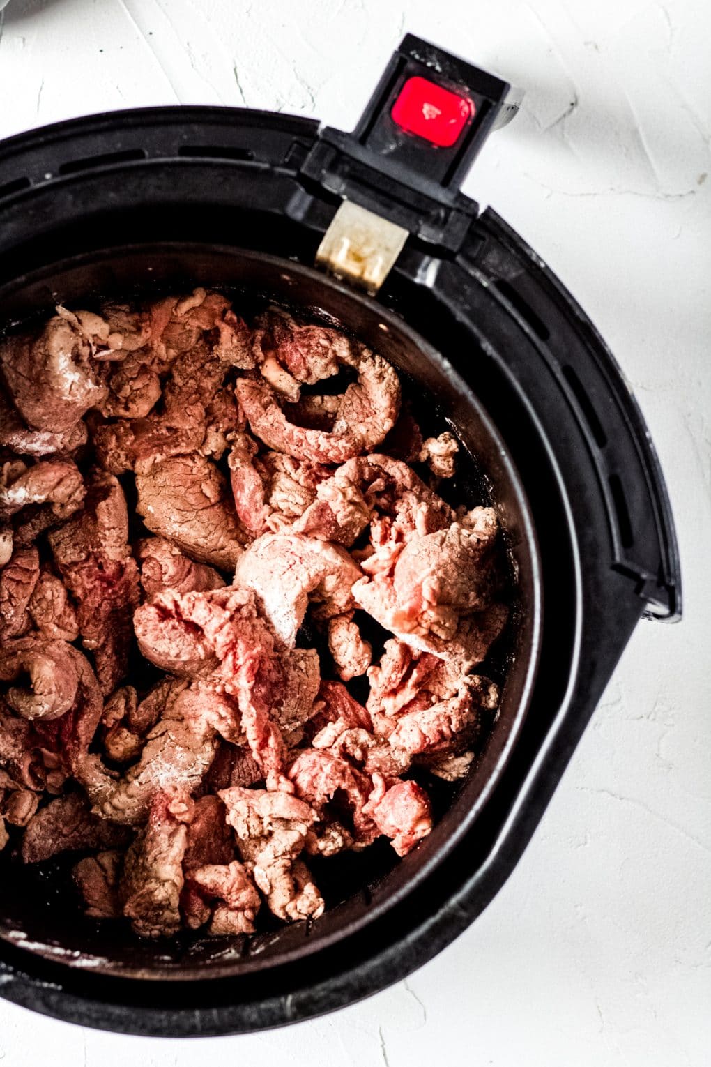 uncooked beef in an air fryer basket
