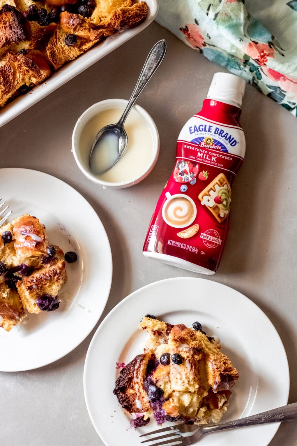 two servings of blueberry french toast bake on white plates and a bottle of Eagle Brand® sweetened condensed milk