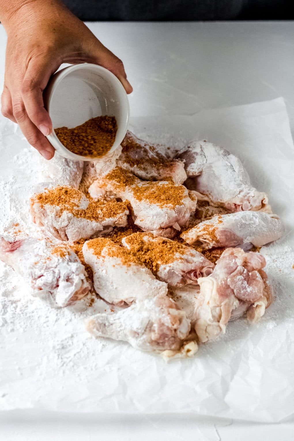raw chicken wings with cajun seasoning rub being sprinkled onto them