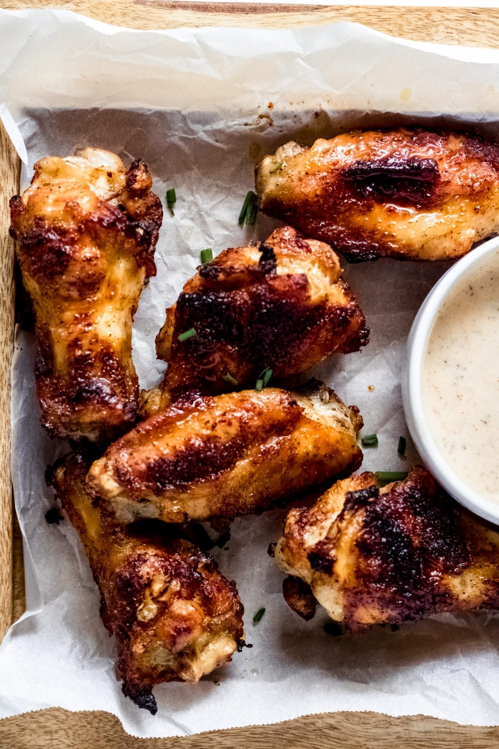 cajun chicken wings on white parchment paper on a wooden cutting board