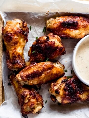cajun chicken wings on white parchment paper on a wooden cutting board
