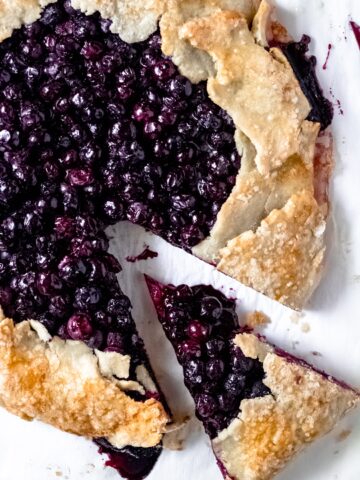 a baked gluten-free blueberry galette with one slice cut out of it