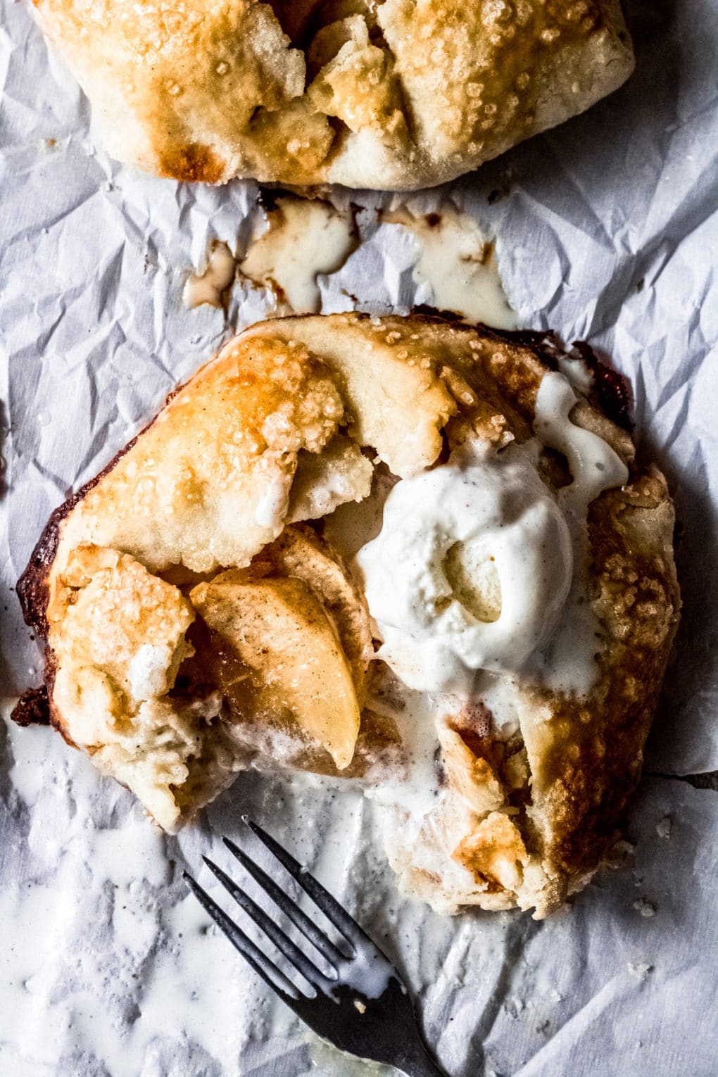a gluten-free mini apple galette with vanilla ice cream. there's a fork and a bite taken out