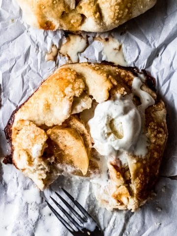 a gluten-free mini apple galette with vanilla ice cream. there's a fork and a bite taken out