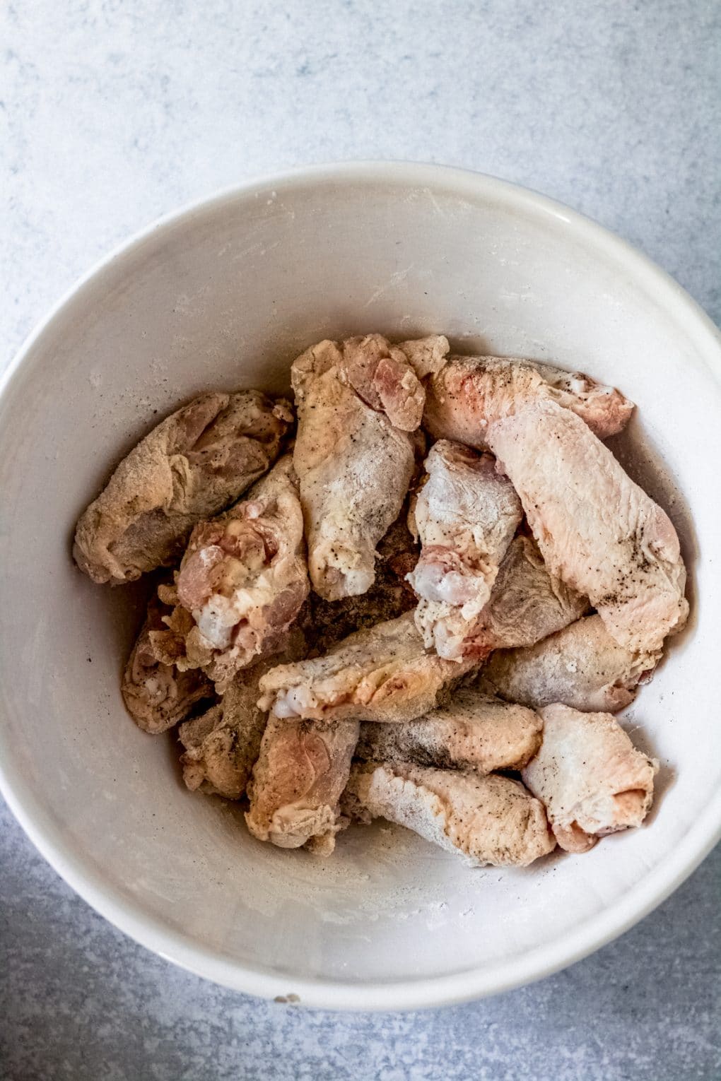 raw chicken wings in a bowl lightly coated with arrowroot starch