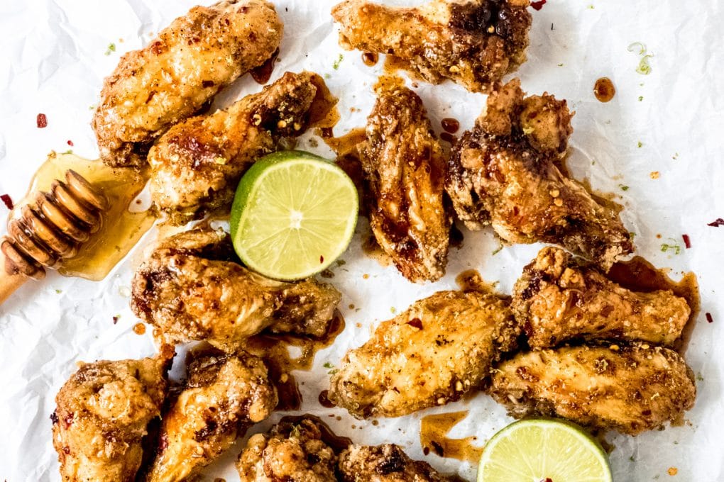honey lime chicken wings with a honey dipper and lime halves