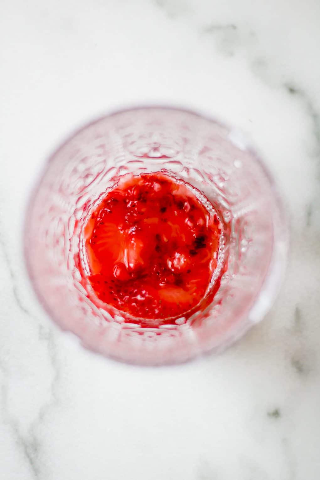 a muddled strawberry in the bottom of a glass