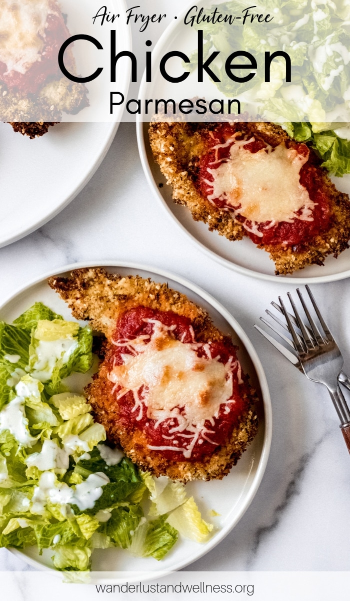 two white plates with air fryer gluten-free chicken parmesan and a side salad