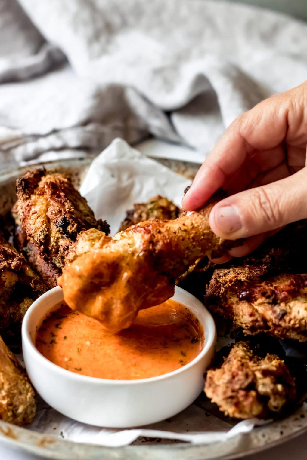 a ranch chicken wing being dipped into buffalo ranch sauce