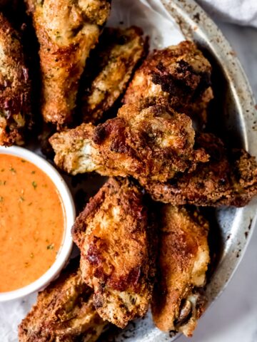 a bowl of ranch chicken wings with a side bowl of buffalo ranch wing sauce
