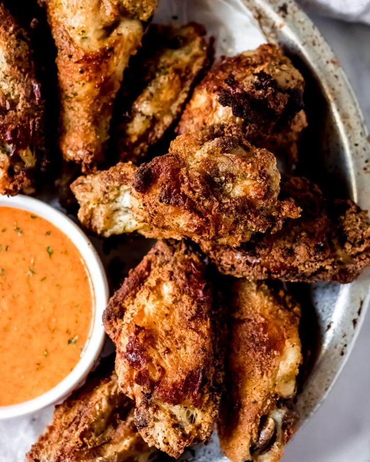 a bowl of ranch chicken wings with a side bowl of buffalo ranch wing sauce