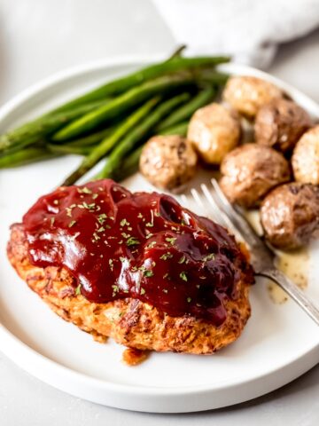 a mini chicken meatloaf on a white plate with green beans and potatoes