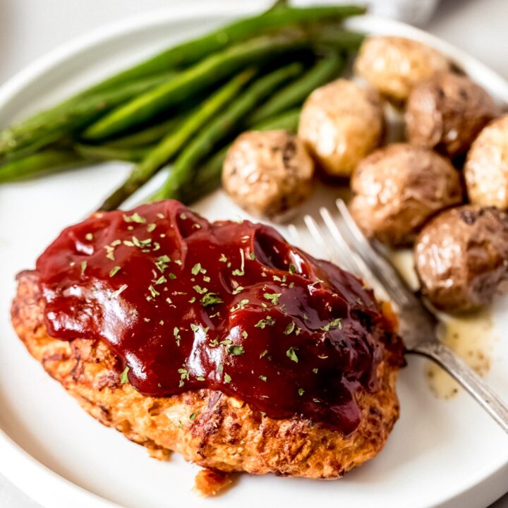 a mini chicken meatloaf on a white plate with green beans and potatoes