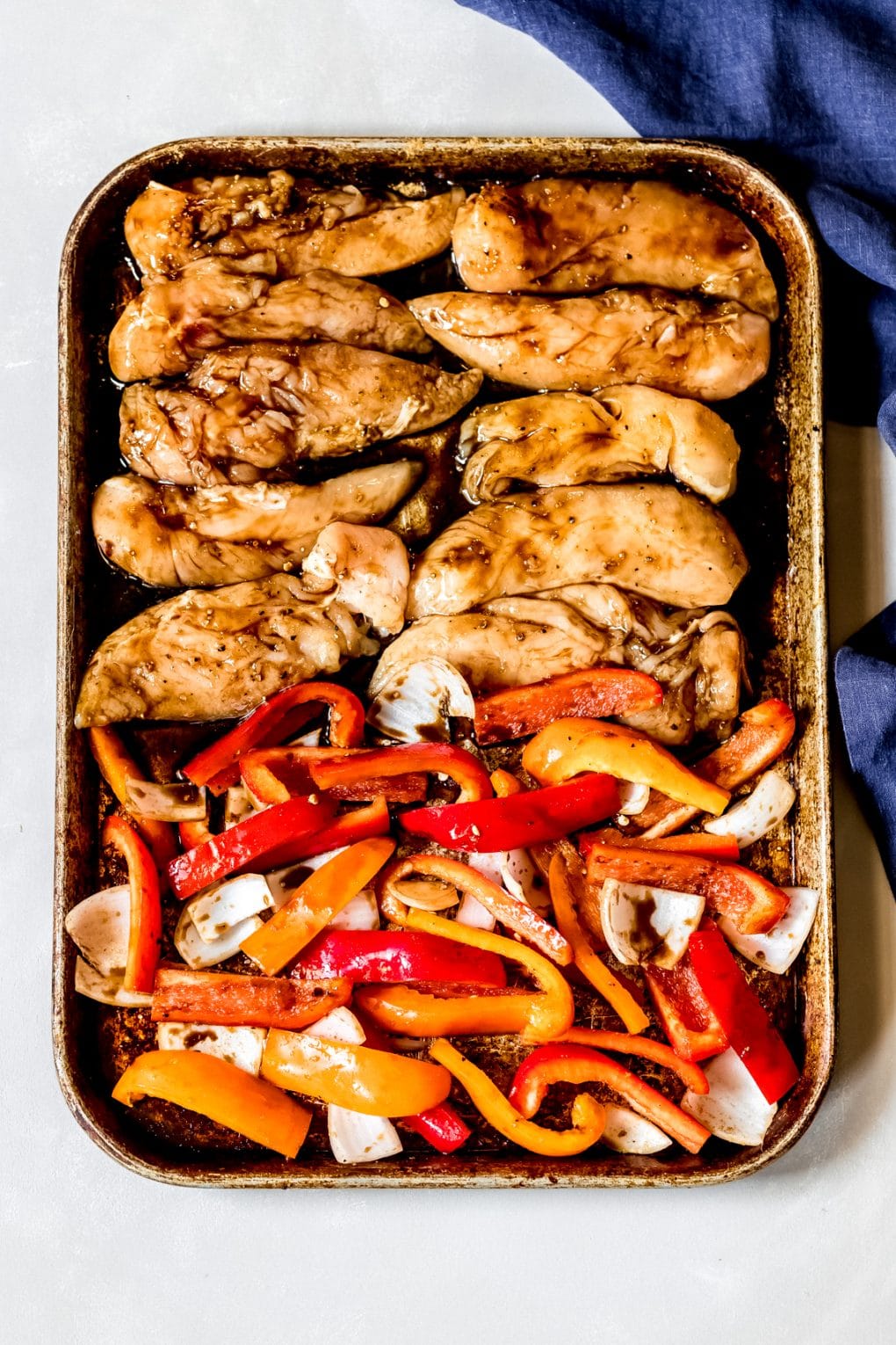 a sheet pan with uncooked chicken and vegetables for fajitas