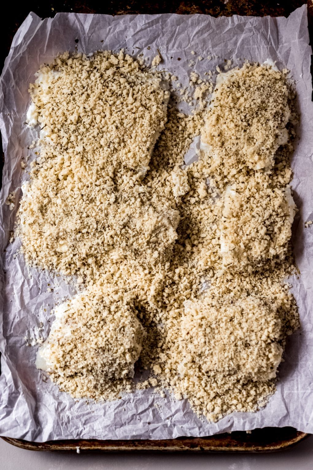 uncooked parmesan crusted cod on a sheet pan