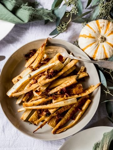 a bowl of maple roasted parsnips on a thanksgiving tablescene