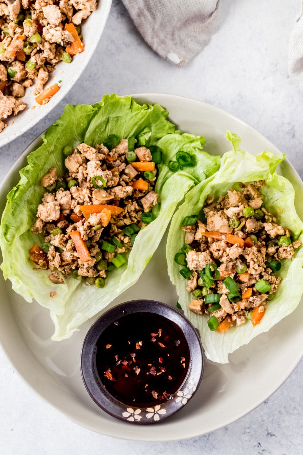 two Asian chicken lettuce wraps on a white plate