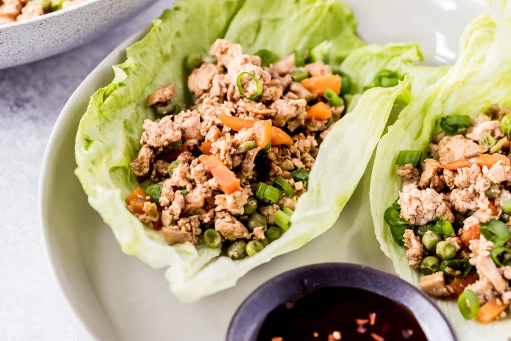 two Asian chicken lettuce wraps served on a white plate