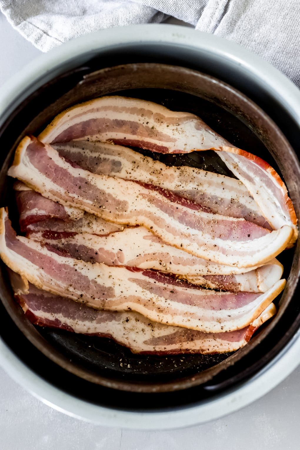 raw bacon in an air fryer basket 