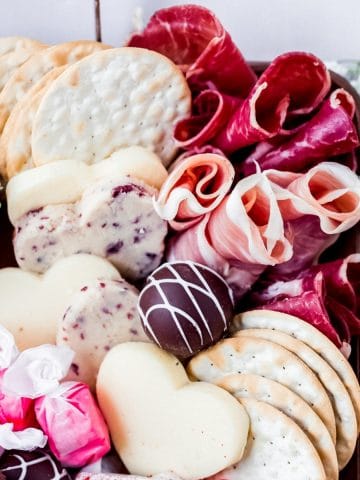 a valentine charcuterie board filled with savory meats and cheese and sweet desserts