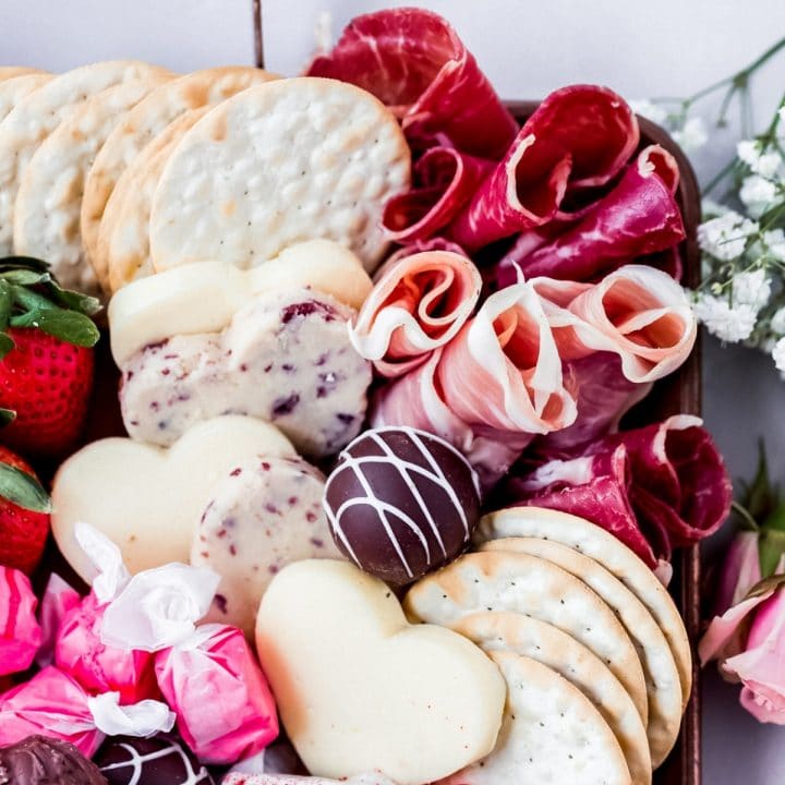 a valentine charcuterie board filled with savory meats and cheese and sweet desserts