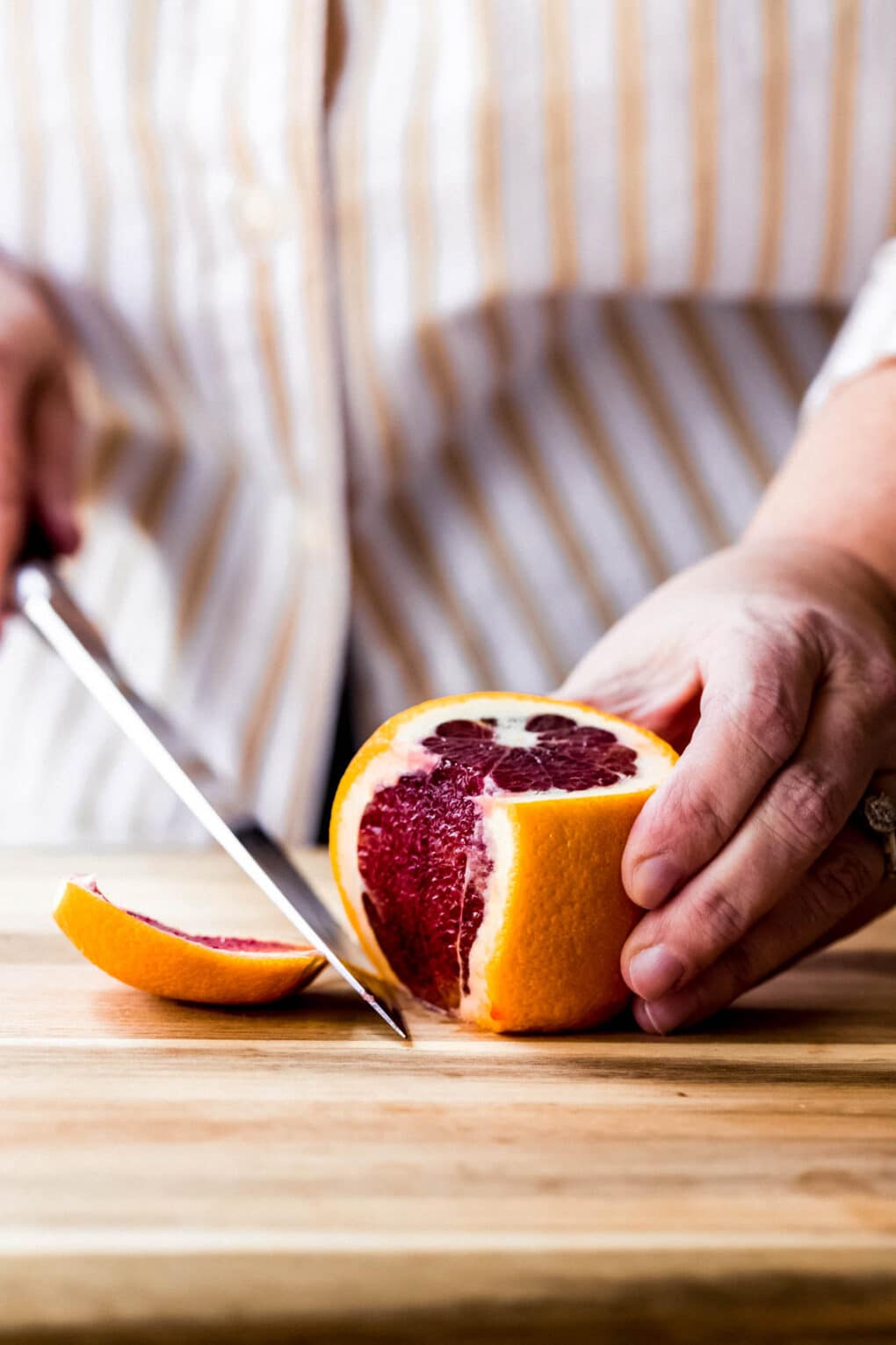 Woman cutting a peel off of an orange